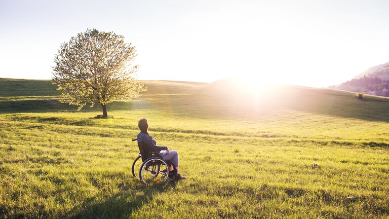 Frau im Rollstuhl schaut in den Sonnenaufgang. | © pixabay