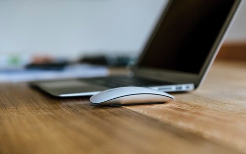 Auf einem braunen Tisch ist ein Laptop und eine Maus.  | © Unsplash