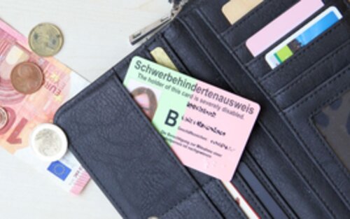 Geöffneter Geldbeutel mit Schlüsselbund, Geld und einem Schwerbehindertenausweis | © familienratgeber.de
