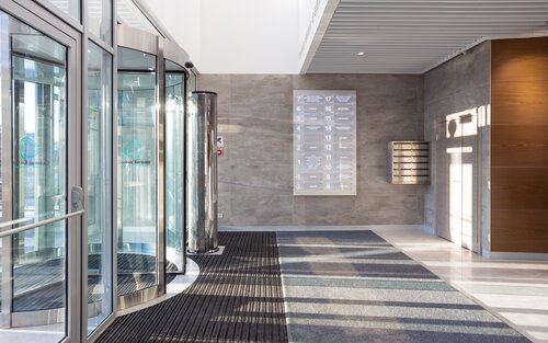 Foto von einem Eingangsbereich eines großen Wohnhauses mit Drehtüren aus Glas. | © Unsplash