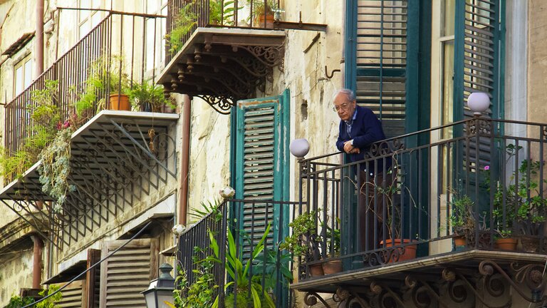 Ein älterer Mann steht auf einem Balkon | © Mihály Köles/unsplash