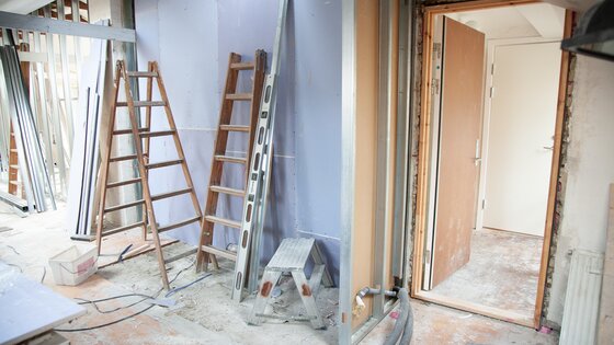 Baustellenszene in einem Haus mit Leitern, Bauschutt, Kabeln und Türrahmen | © pexels