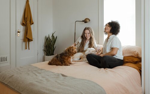 Zwei Menschen und ein Hund sitzen auf einem Bett | © unsplash