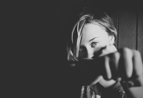 Schwarz-Weiß Foto von einer Frau, die in die Kamera schaut und die geballte Faust ausstreckt. | © Unsplash