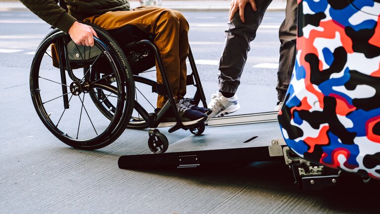 Eine Person im Rollstuhl fährt über eine Rampe in ein Auto | © Andi Weiland/Gesellschaftsbilder.de