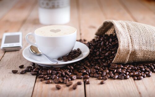 Kaffeebohnen und eine Kaffeetasse liegen auf einem Holztisch. | © Mike Kenneally/unsplash