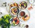 Eine Aufnahme eines Tisches mit verschiedenen Frühstücksgerichten – Haferbrei mit Obst, Waffeln, Honig, Milchkännchen, Karaffen, Kaffee | © Brooke Lark/unsplash