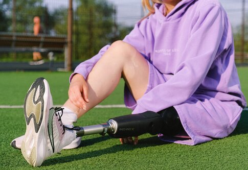 Frau mit Beinprothese, die auf einem Rasen sitzt | © pexels