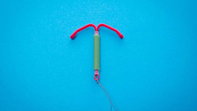 Eine rot-grüne Hormonspirale vor blauem Hintergrund. | © Reproductive Health Supplies Coalition/unsplash
