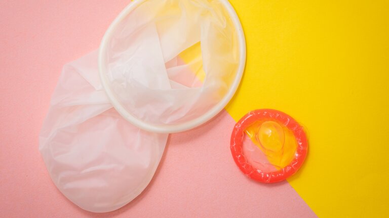 Auf dem Foto sieht man ein Kondom sowie ein Frauenkondom vor gelb-rosa Hintergrund. | © Reproductive Health Supplies Coalition/unsplash