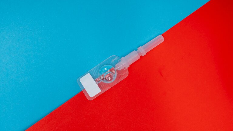 Eine Spritze mit Flüssigkeit gefüllt vor rot-blauem Hintergrund. | © Reproductive Health Supplies Coalition/unsplash