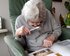 Eine ältere Dame sitzt auf einem Sessel und betrachtet mithilfe einer Lupe ein Fotoalbum. | © pixabay