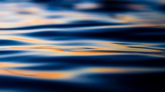 Wasser mit leichten Wellen und Spiegelung von oranger Farbe | © Jason Leung/ unsplash 