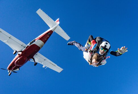 Foto von zwei Fallschirmspringer*innen, die aus einem Flugzeug springen. | © Unsplash