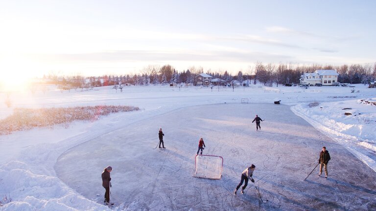 Foto von einer Gruppe Menschen, die im Winter auf einem Spielfeld Eishockey spielen. | © Unsplash
