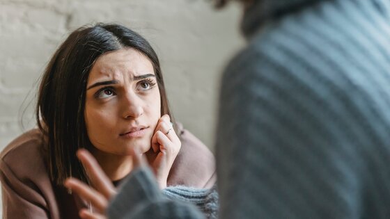 Eine Frau mit einem besorgten Gesichtsausdruck hört einer anderen Person zu. | © Pexels/Liza Summer