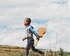 Ein Junge rennt mit einer Ukulele in der Hand über ein Feld | © unsplash