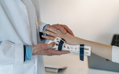 Arzt hilft einer Person beim Anziehen einer Handschiene | © Unsplash