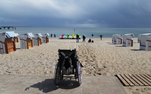 Leerer Rollstuhl an Strandpromenade