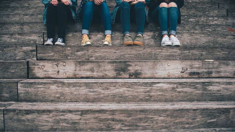 Vier Jugendliche sitzen auf einer Treppe. 
 | © unsplash